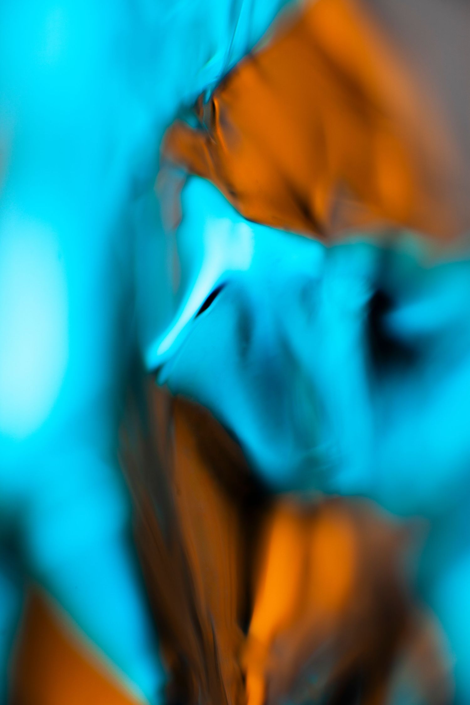 Abstract macro photography featuring swirling cyan and orange hues creating a vibrant, fluid artistic composition.
