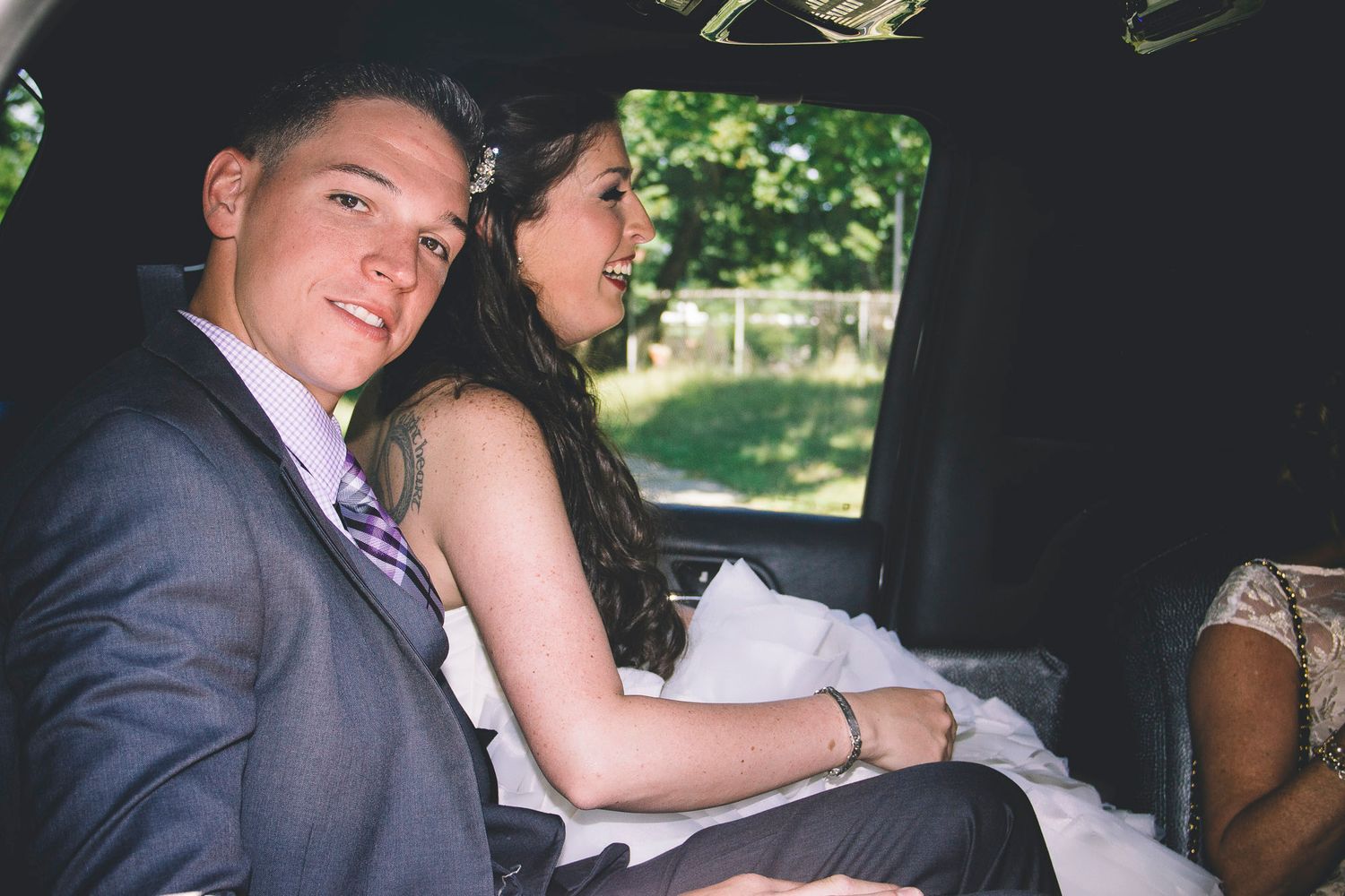 Bride and groom share a tender moment together in the backseat of a wedding limousine.