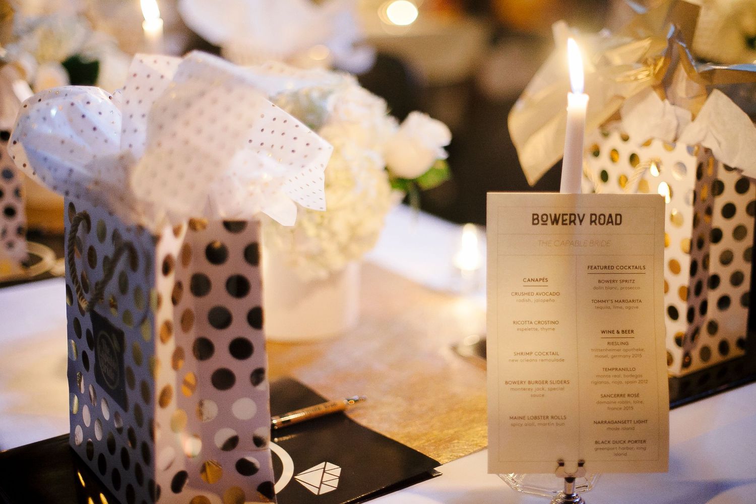 Bowery Road menu card beside polka dot gift bags and white floral centerpiece.