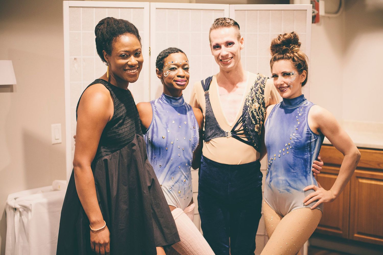 Four female performers posing backstage in sparkly costumes after a show.