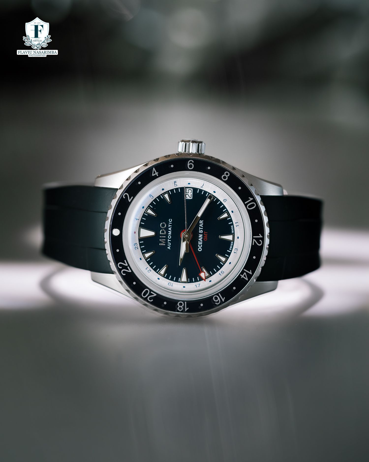 Mido Ocean Star GMT watch with black dial and bezel on black rubber strap against grey background.