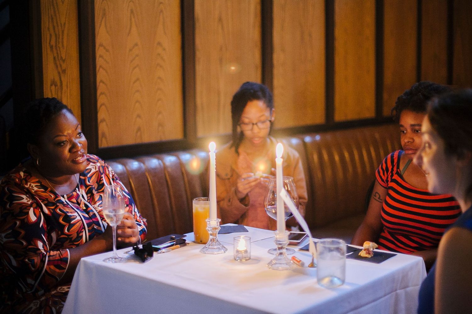Women enjoying a candlelit dinner at The Capable Bride wedding planning event with orange cocktails.