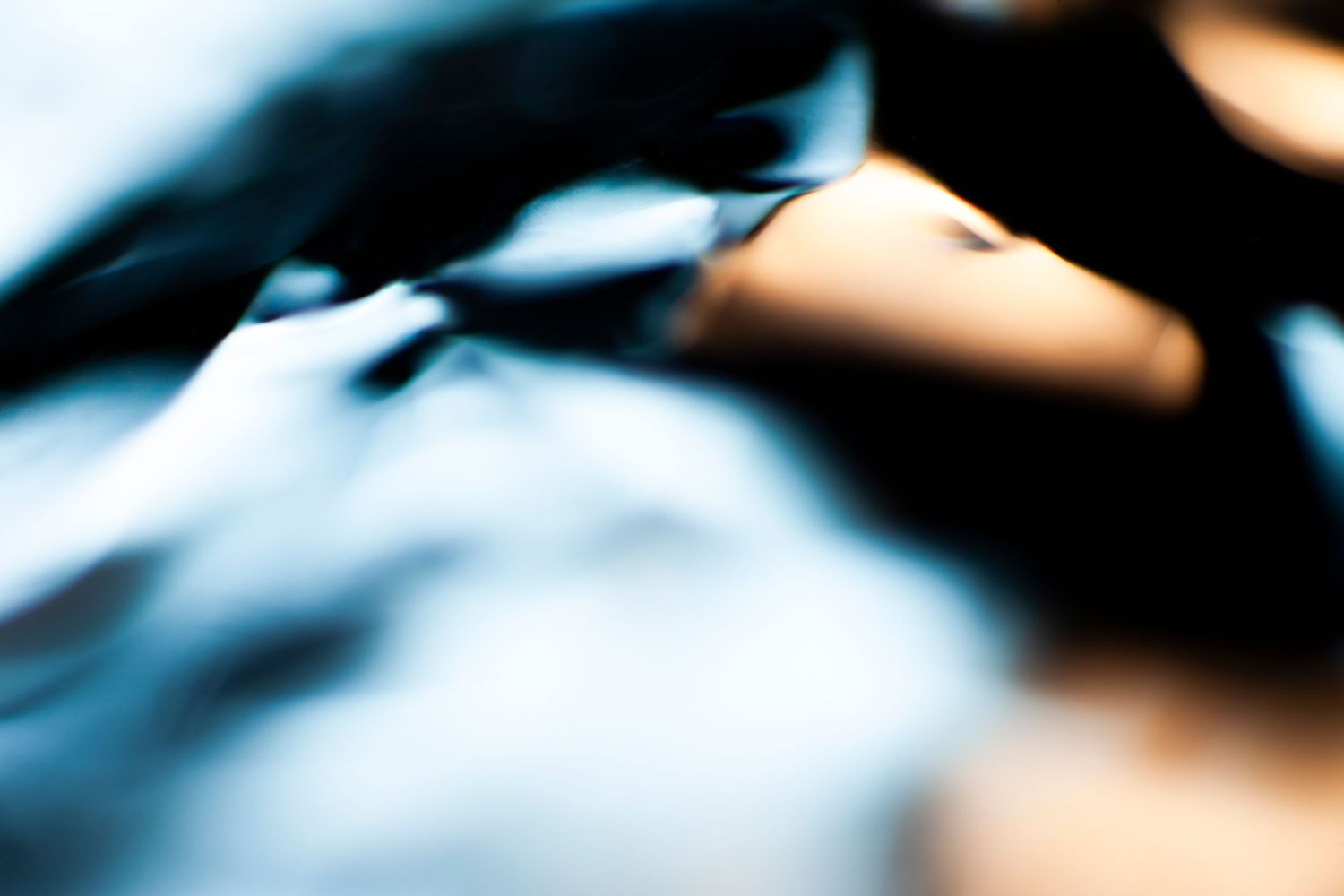 Abstract close-up of dark blue and black fabric with soft bokeh lighting creating a moody, artistic texture.