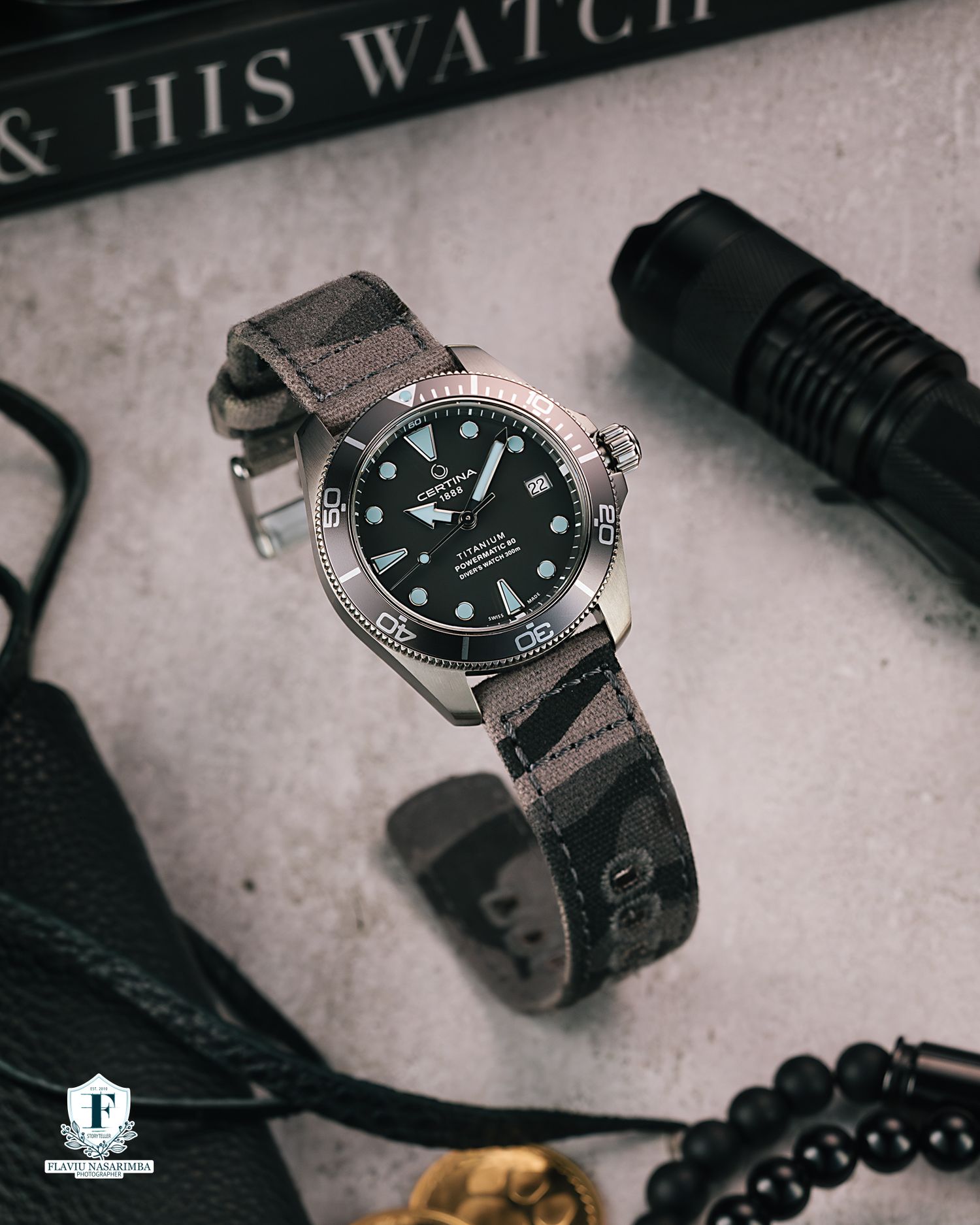 Omega Seamaster titanium dive watch with black dial on canvas NATO strap beside flashlight.