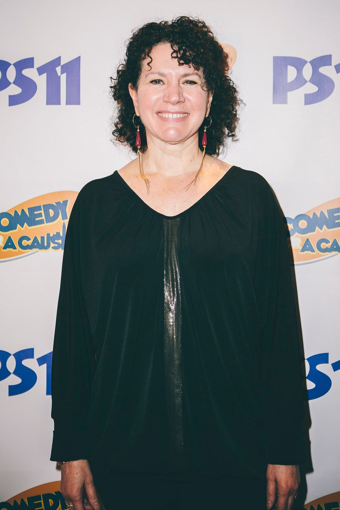 Smiling woman with curly hair posing at PS11 Comedy for a Cause charity event.
