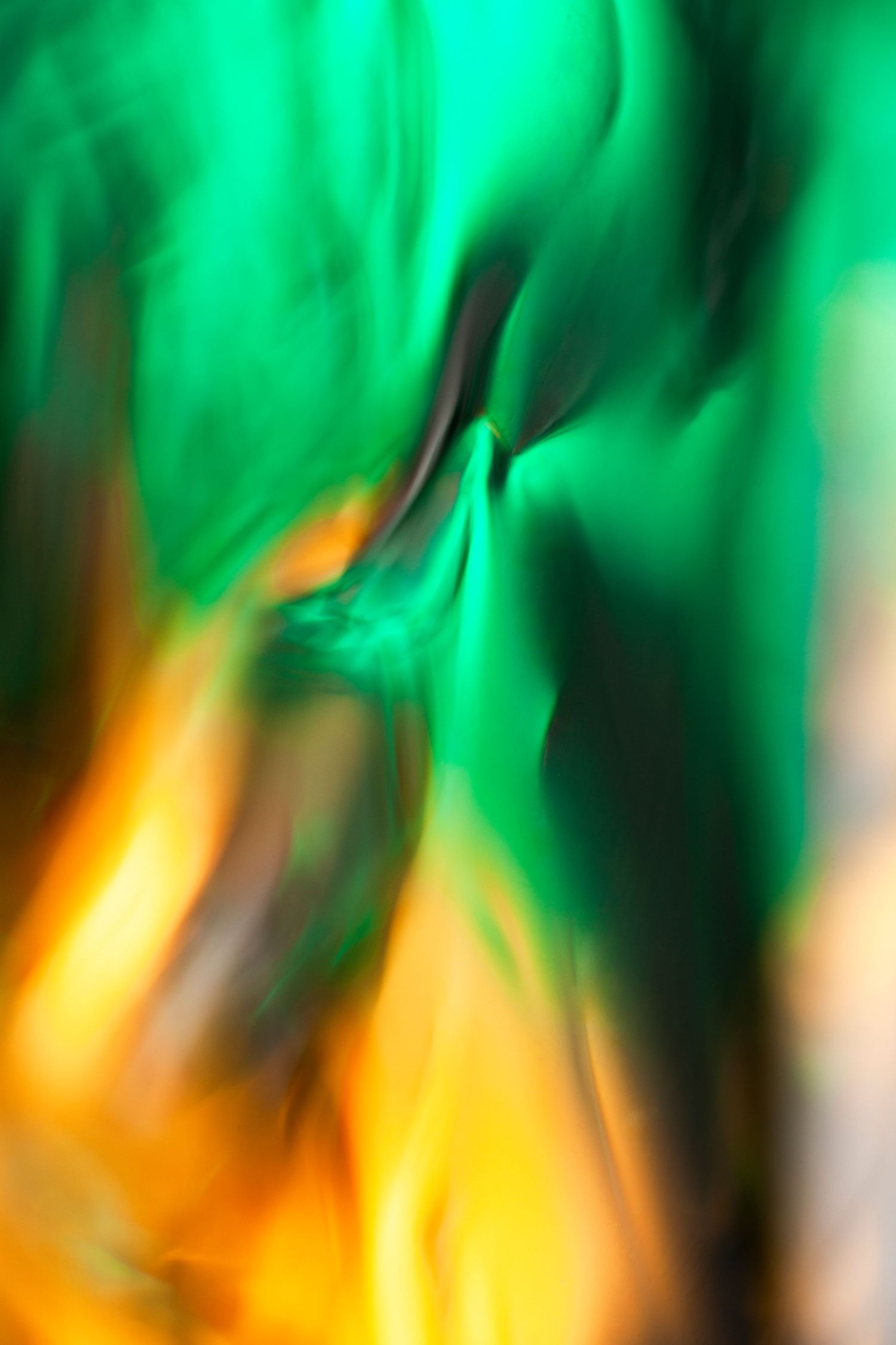 Abstract blurred green and orange flames creating a vibrant, flowing motion effect with dark contrasting streaks.