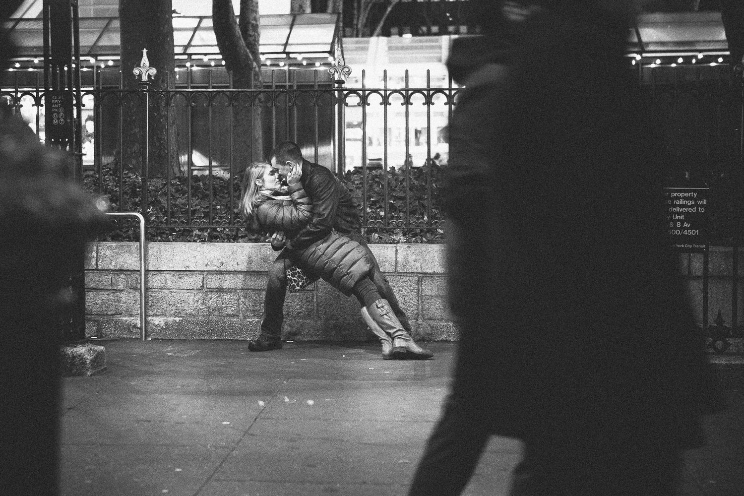 Black and white photo of couple embracing on busy city street at night.