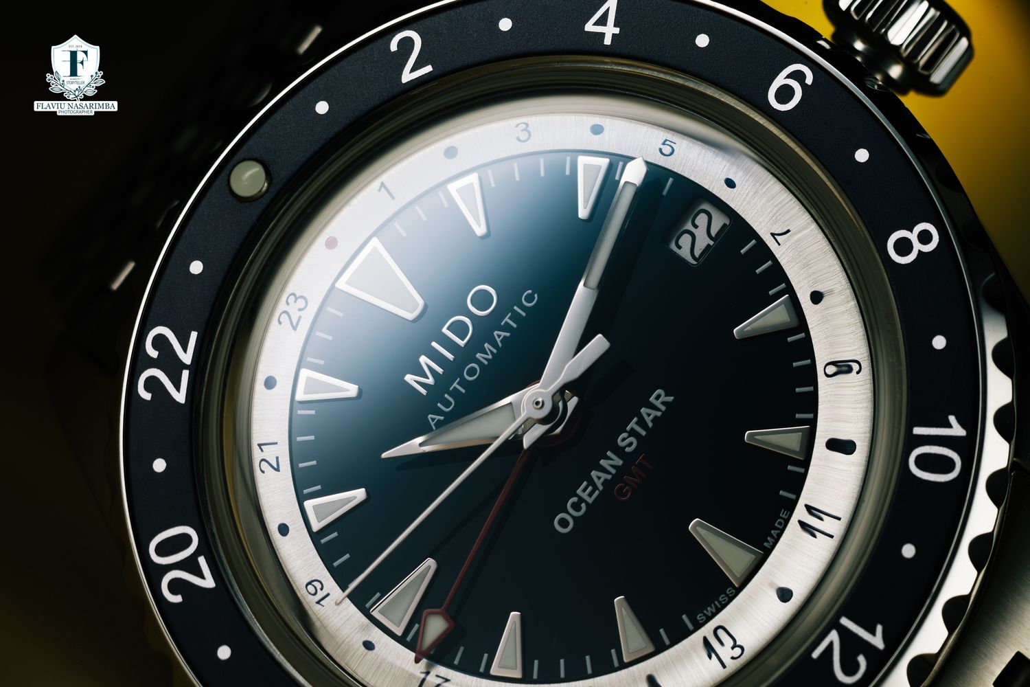 Close-up of a Mido Ocean Star automatic GMT watch with black bezel and white dial markers.