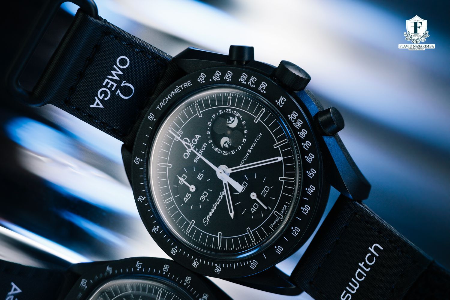 Omega x Swatch Speedmaster Moonwatch black chronograph with moon phase complication on dark background.