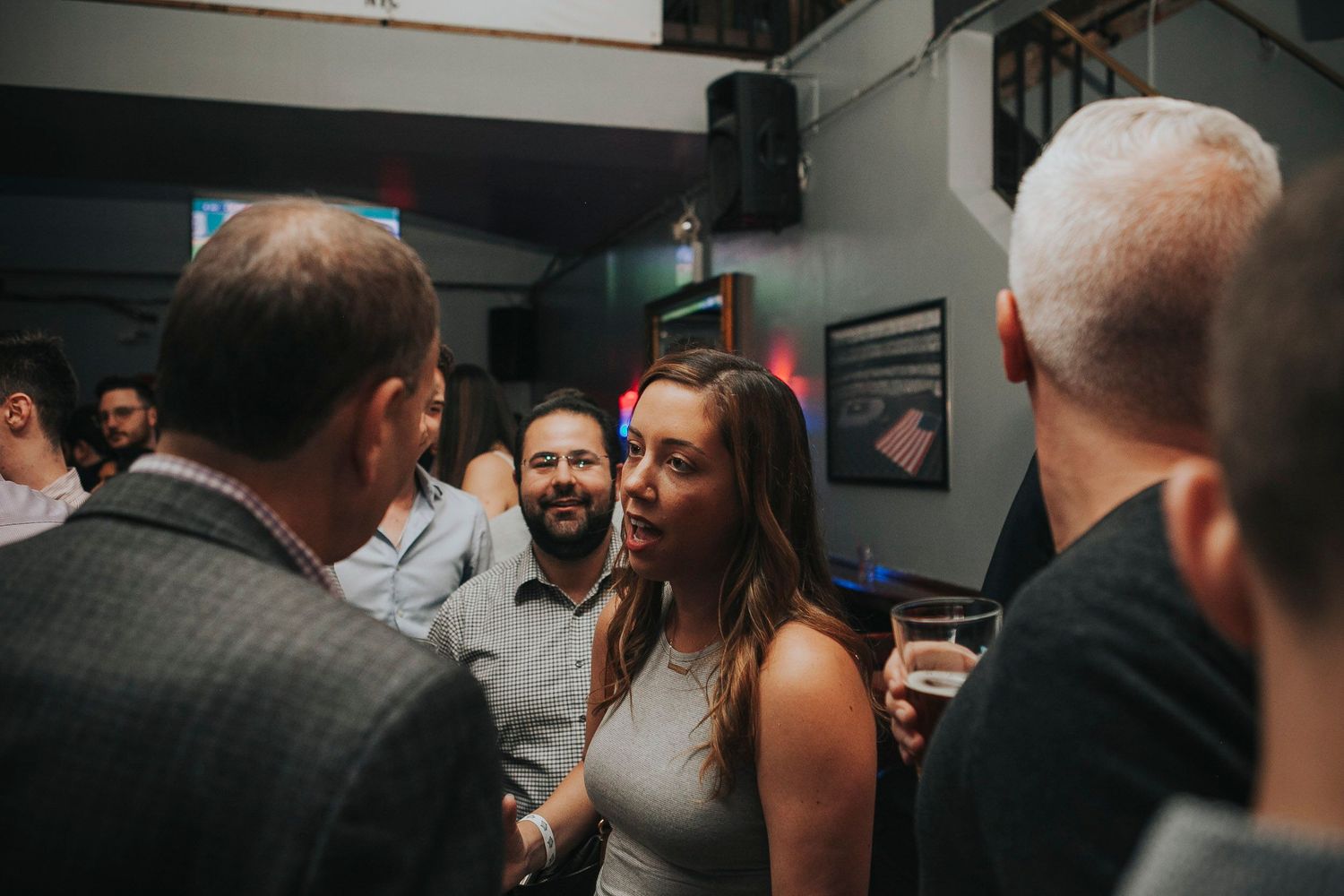 Group of professionals mingle and chat at an indoor networking event.