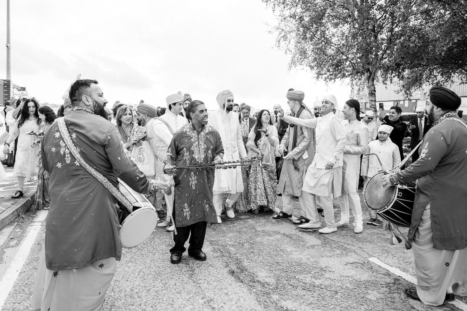 Wedding guests gather outside on a sunny day to celebrate the newlyweds.