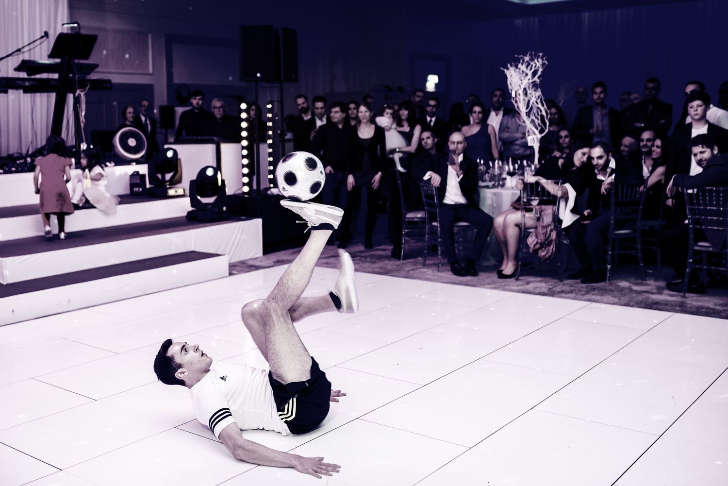 Breakdancer performing dynamic power moves and spins on a white dance floor during a street performance.