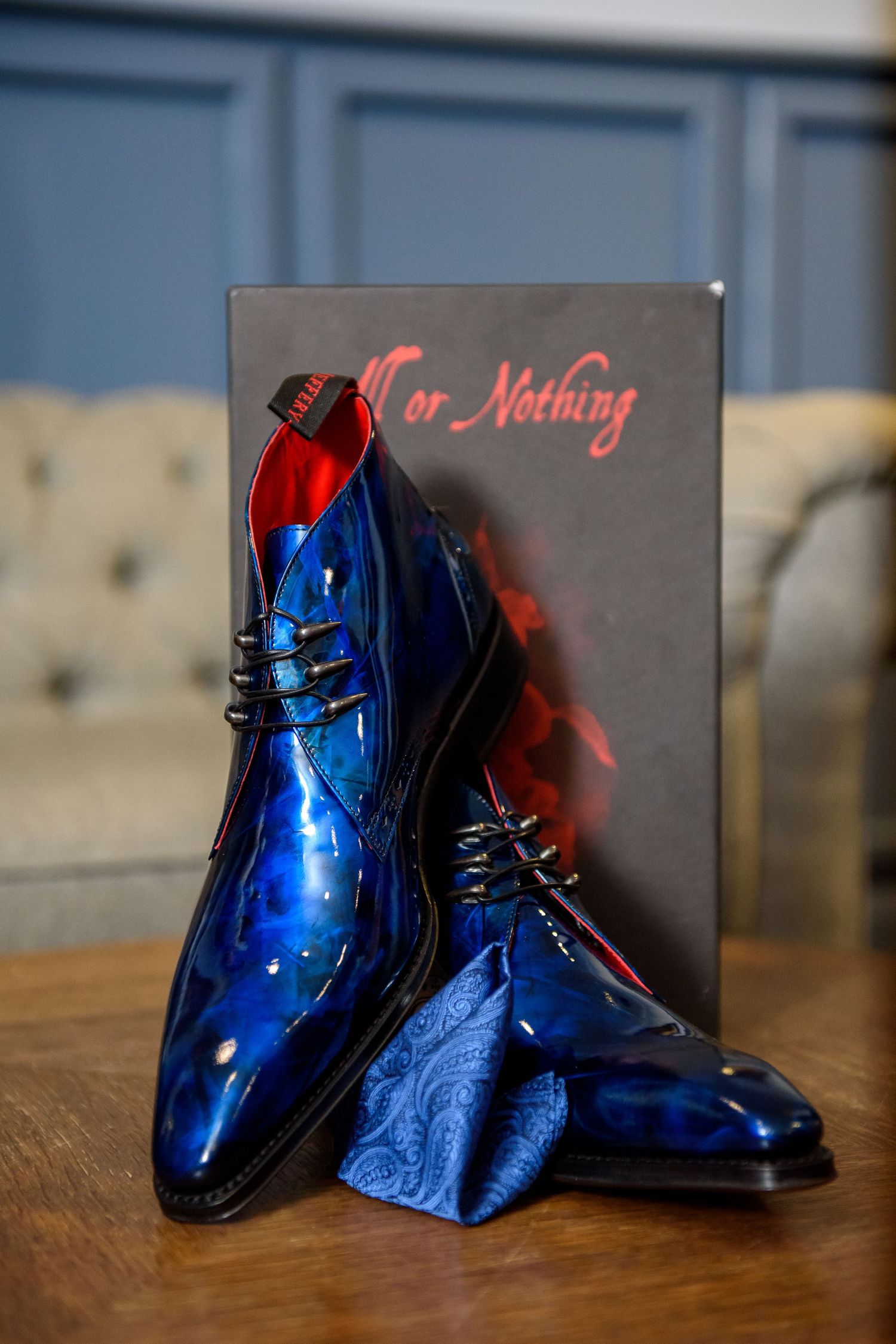 Shiny metallic blue dress shoes with black laces displayed next to a 