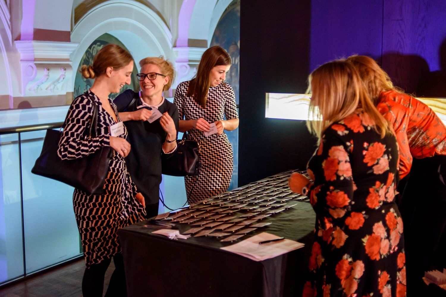 Event attendees gathered around a display table at a corporate function.