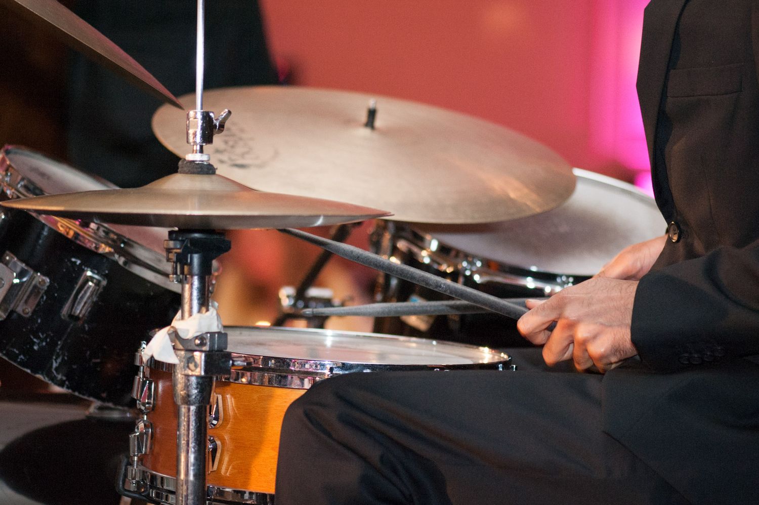 Close-up of drummer performing on cymbals with dramatic stage lighting.