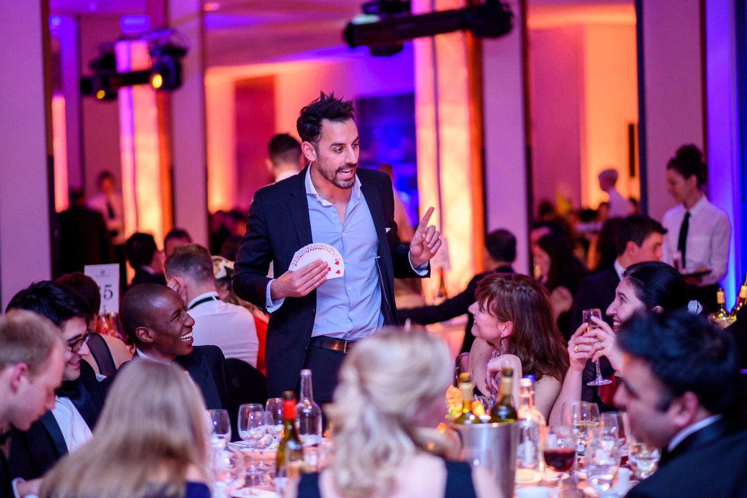 Wedding reception venue with dramatic purple and pink uplighting illuminating the dining area.