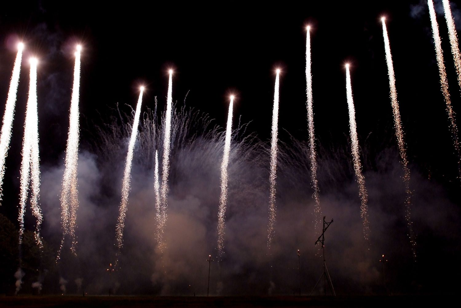 Spectacular fireworks display lighting up the night sky with bright white bursts and trails.