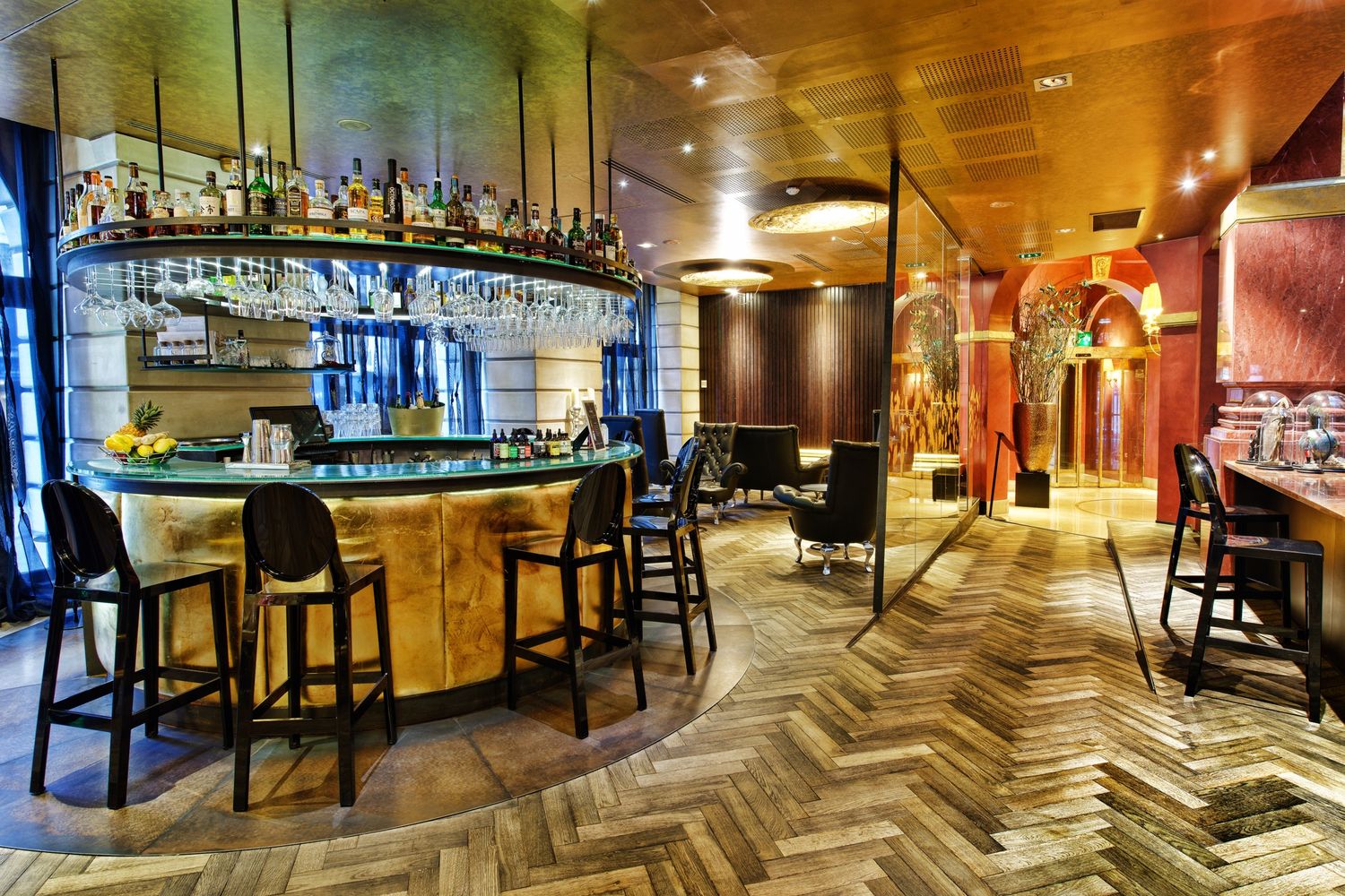 Modern bar lounge area with herringbone wood floors and sleek furniture creates an upscale ambiance.
