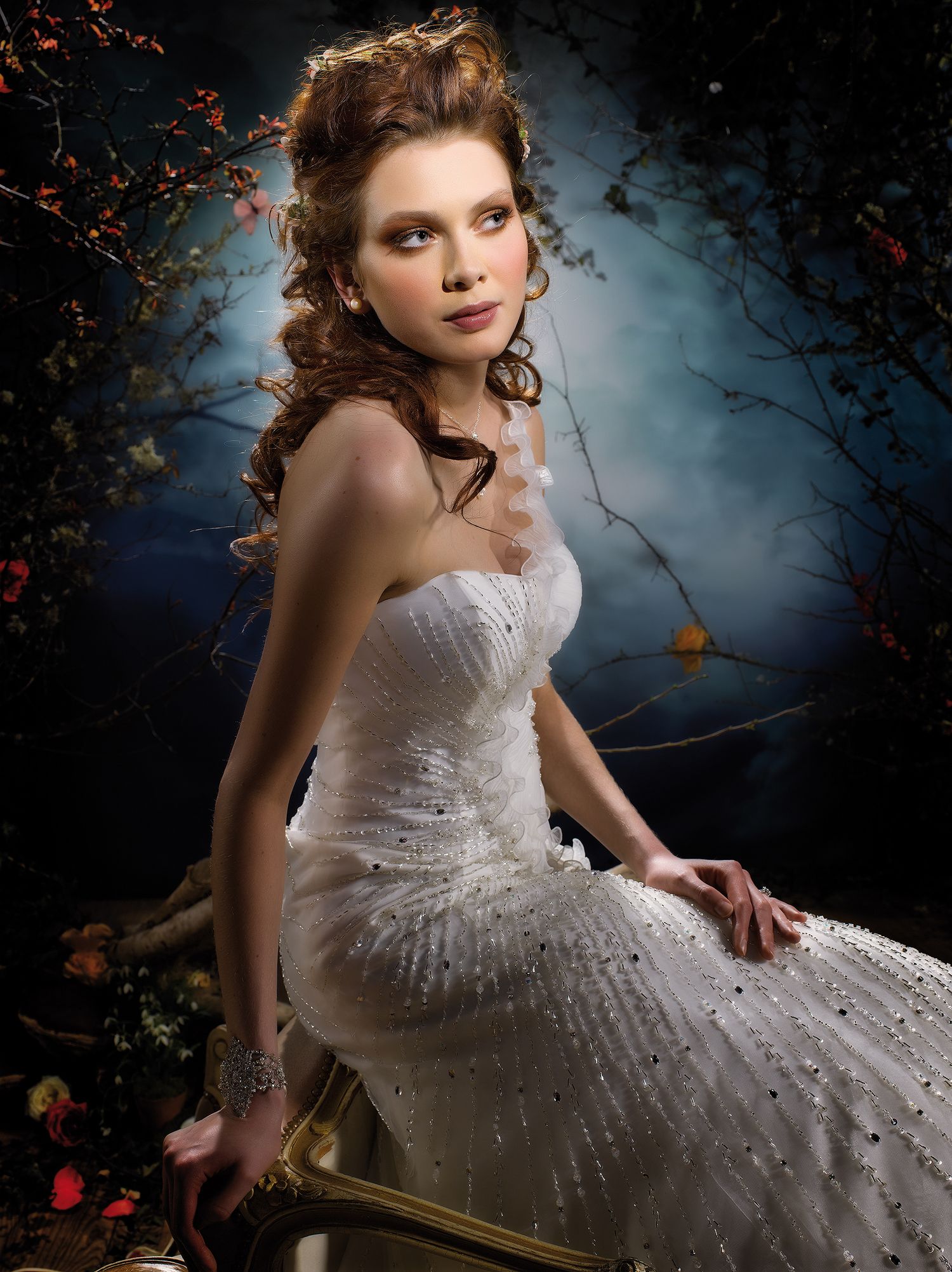 Woman in a sparkling white strapless ball gown posed in a mystical forest setting with blue misty background.
