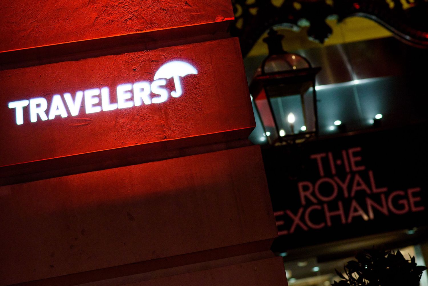Illuminated business signage with red accent lighting creates dramatic nighttime atmosphere.