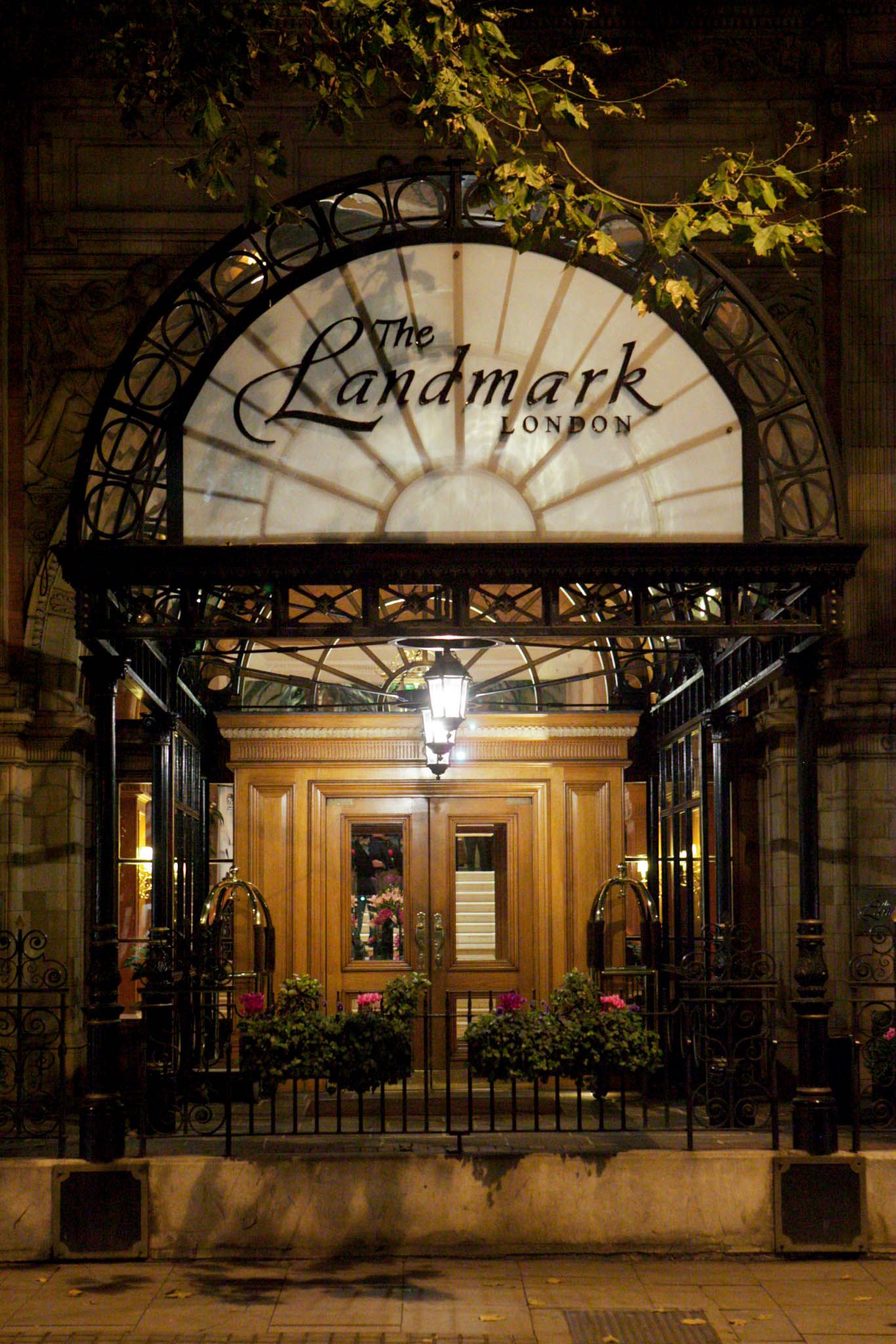 Illuminated entrance of The Landmark hotel with ornate ironwork archway at night.