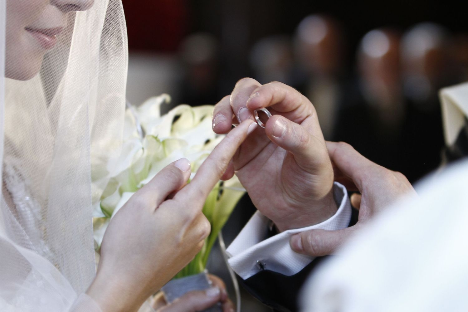 A close-up shot of hands exchanging wedding rings during a traditional ceremony.
