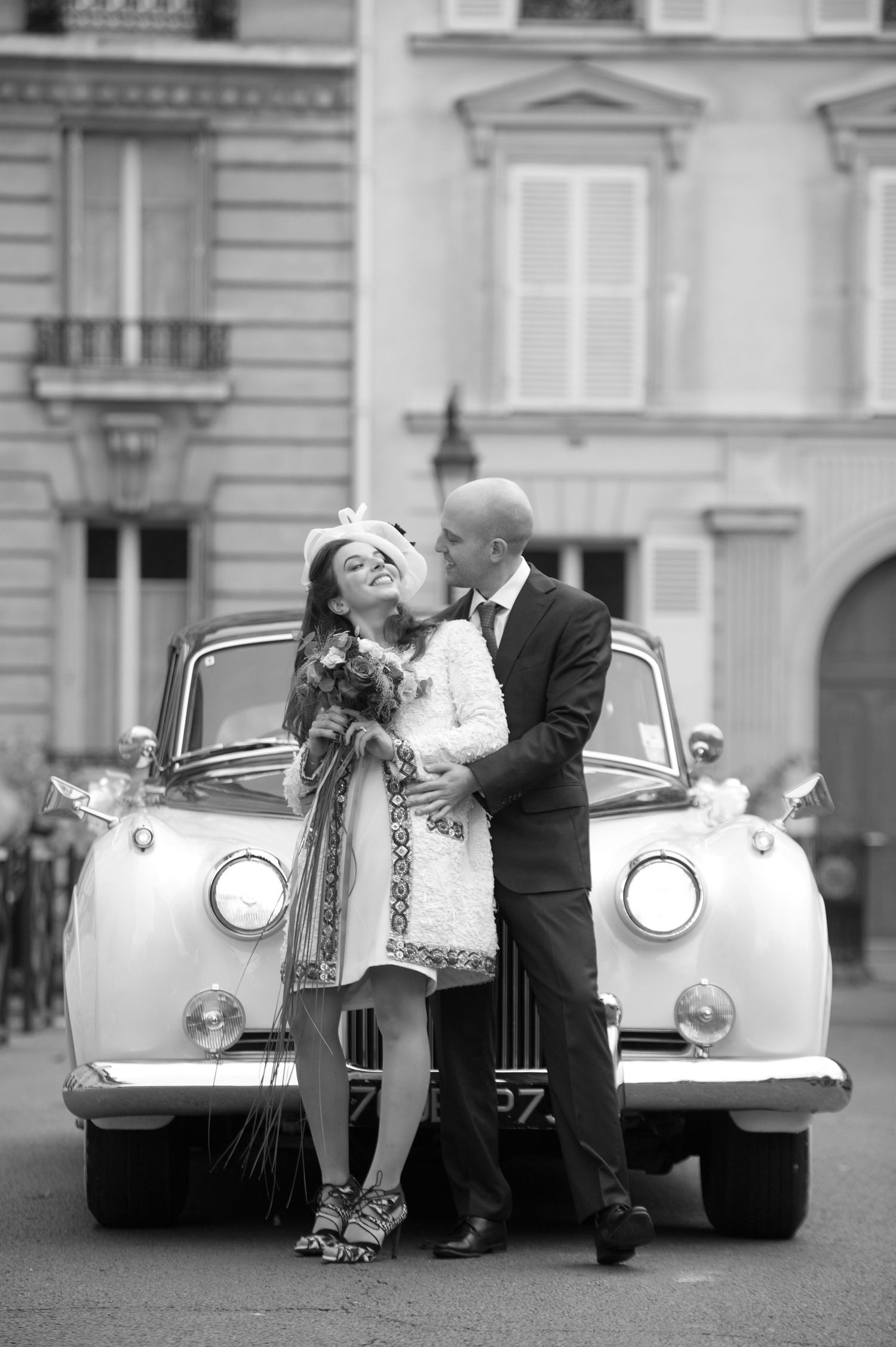 A romantic black and white photo sequence showing a couple with a vintage luxury car in an elegant European setting.