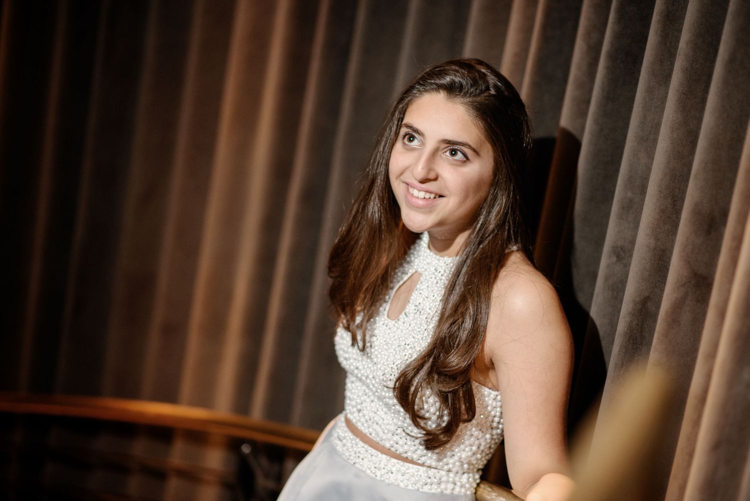 A bride in a white lace wedding dress poses in front of brown curtains in a series of elegant portraits.