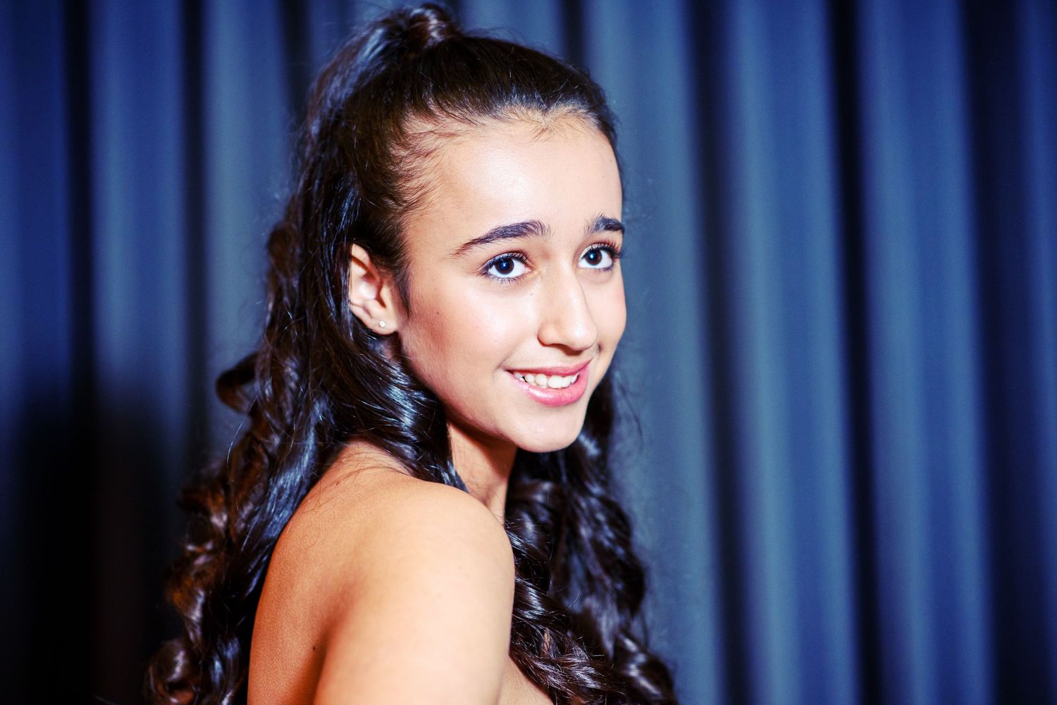 A collage of four photos showing a person with dark hair smiling against a blue curtain backdrop.