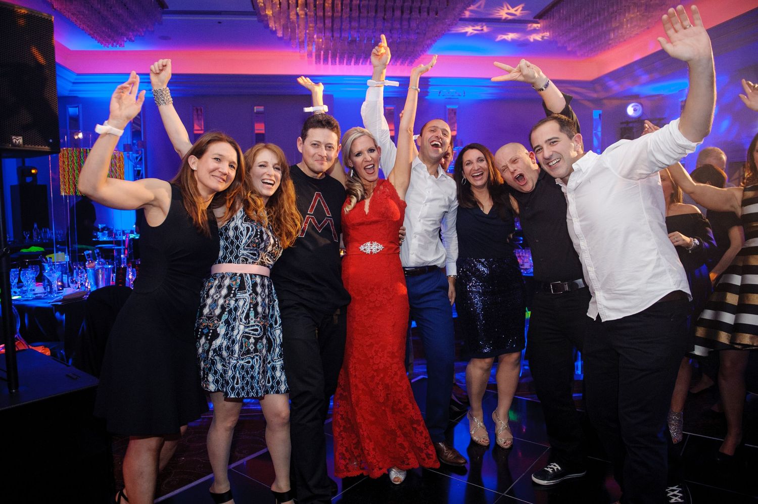 People dancing and socializing in a nightclub with blue lighting and festive atmosphere.