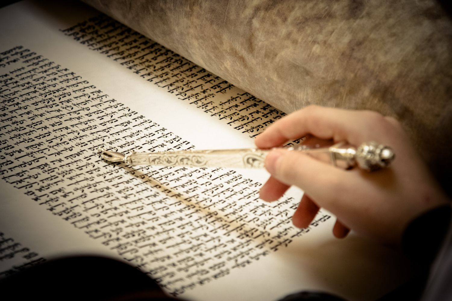 A hand points to text on a page of an old book or manuscript with dense typography.