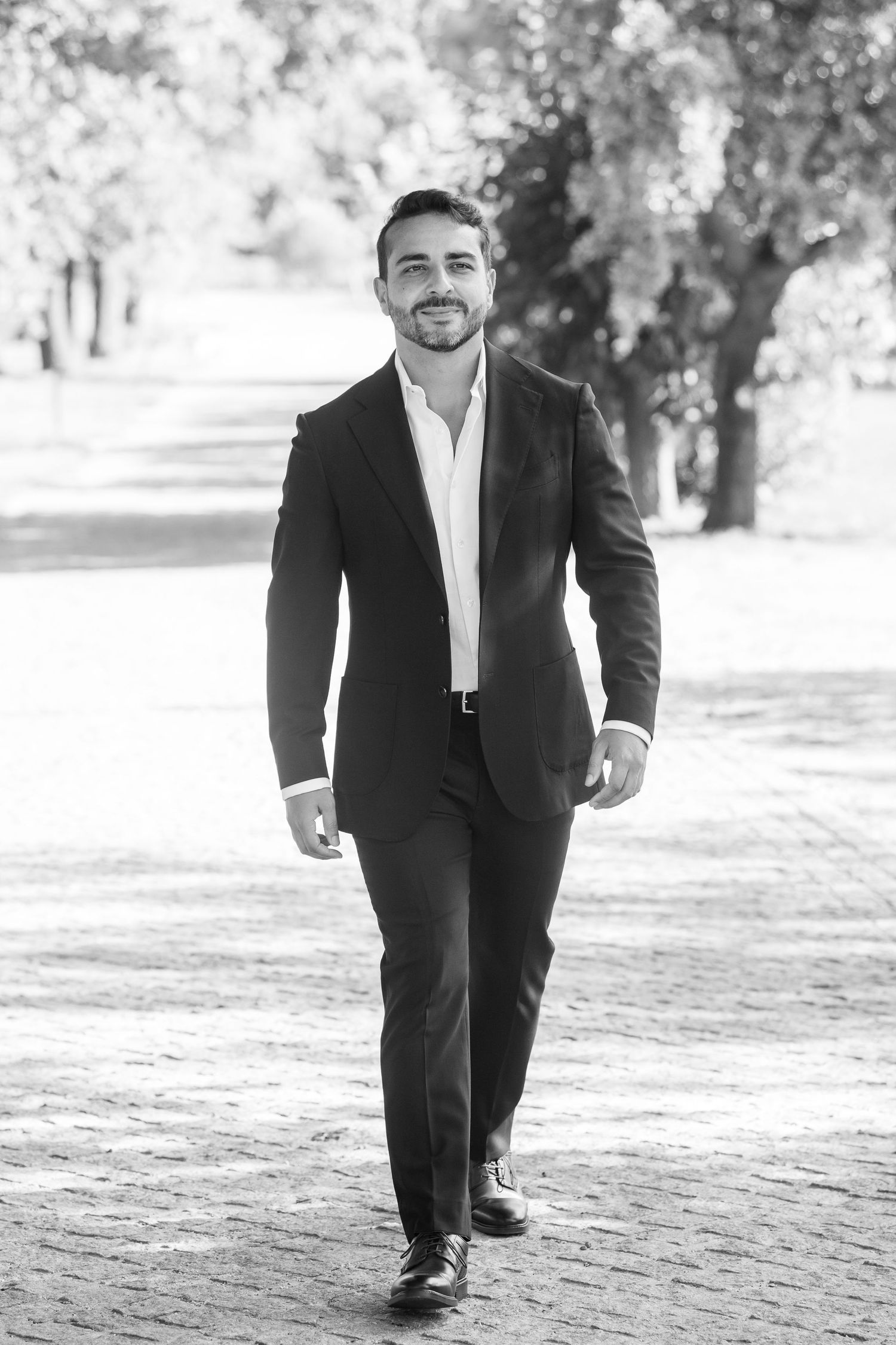Black and white photo series of a person in formal attire walking on a path outdoors.