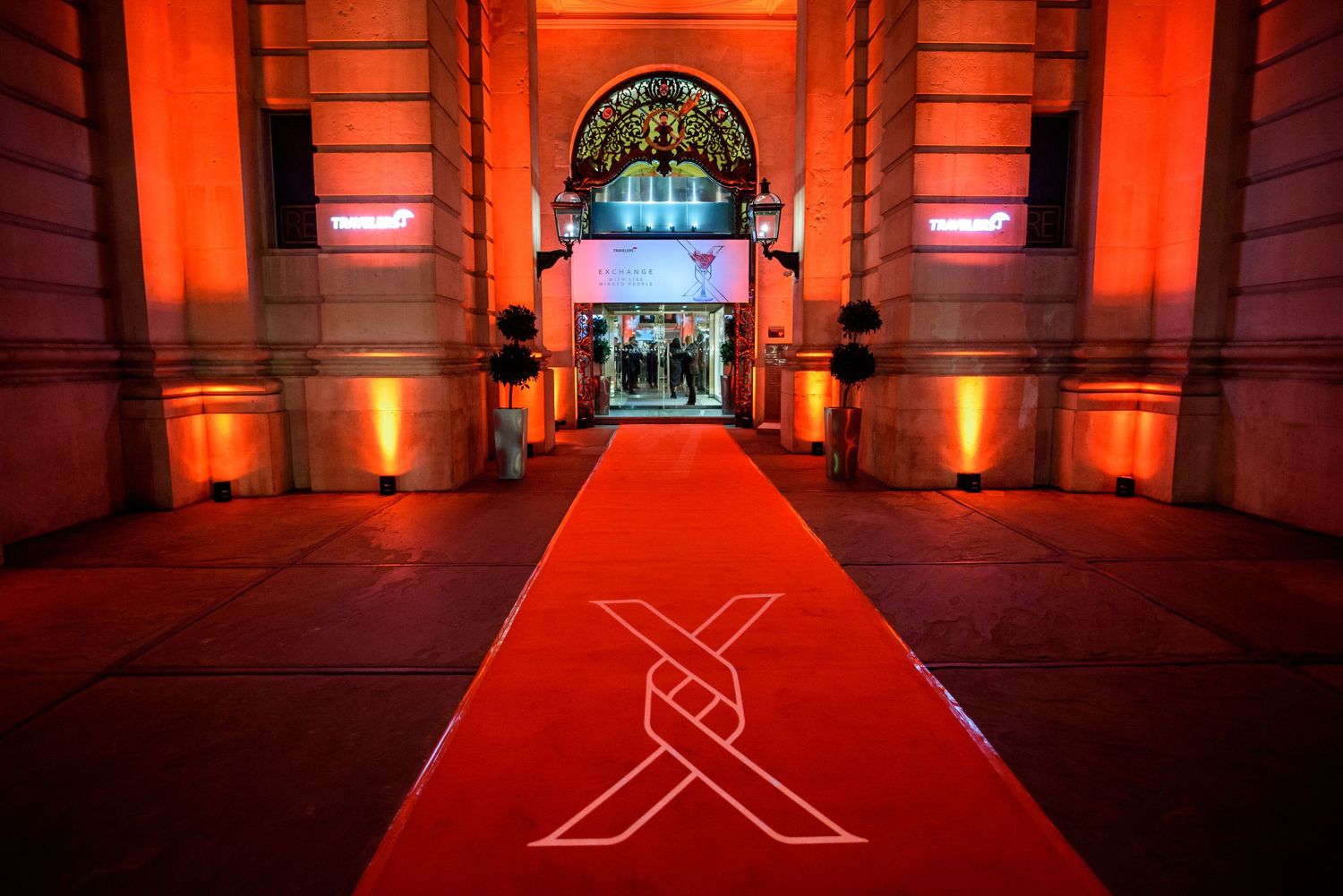 Red-lit architectural facade with dramatic lighting and arched doorways.