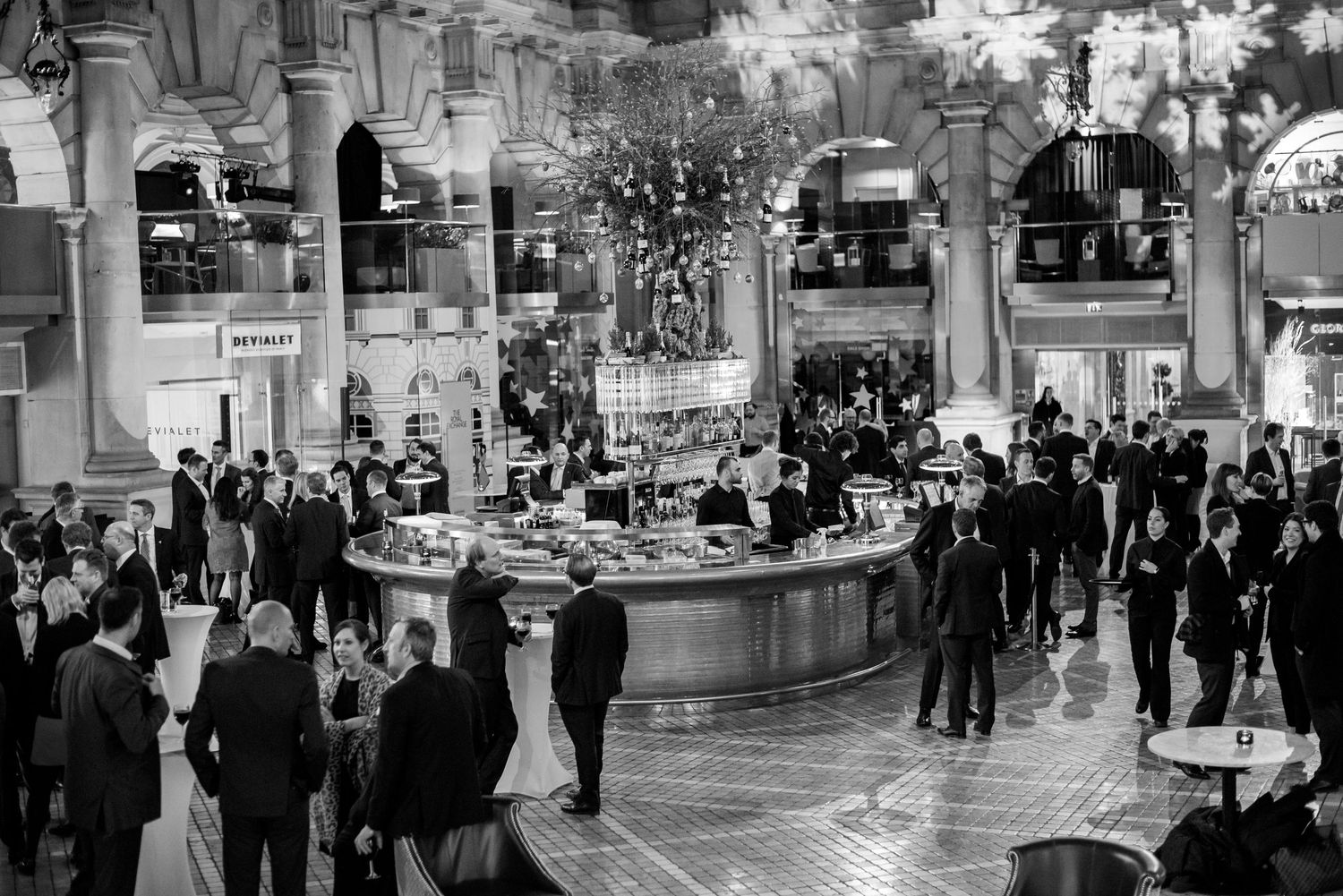 Elegant formal event venue with guests mingling in a grand hall under ornate lighting.