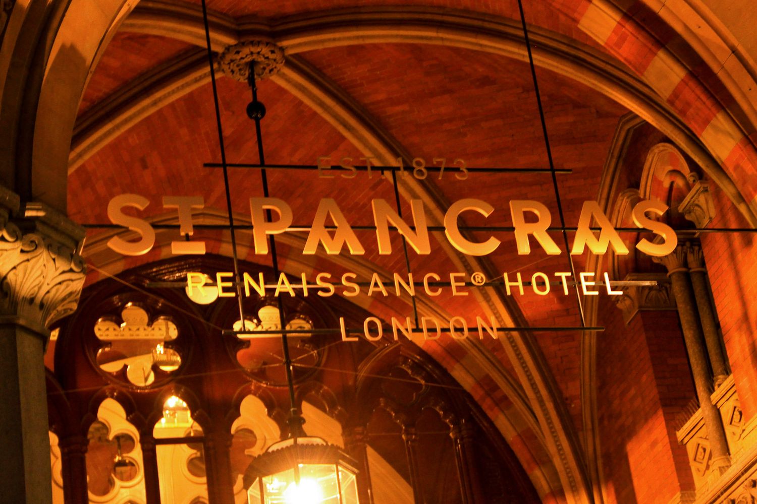Ornate architectural details of St Pancras Renaissance Hotel illuminated in warm orange lighting.