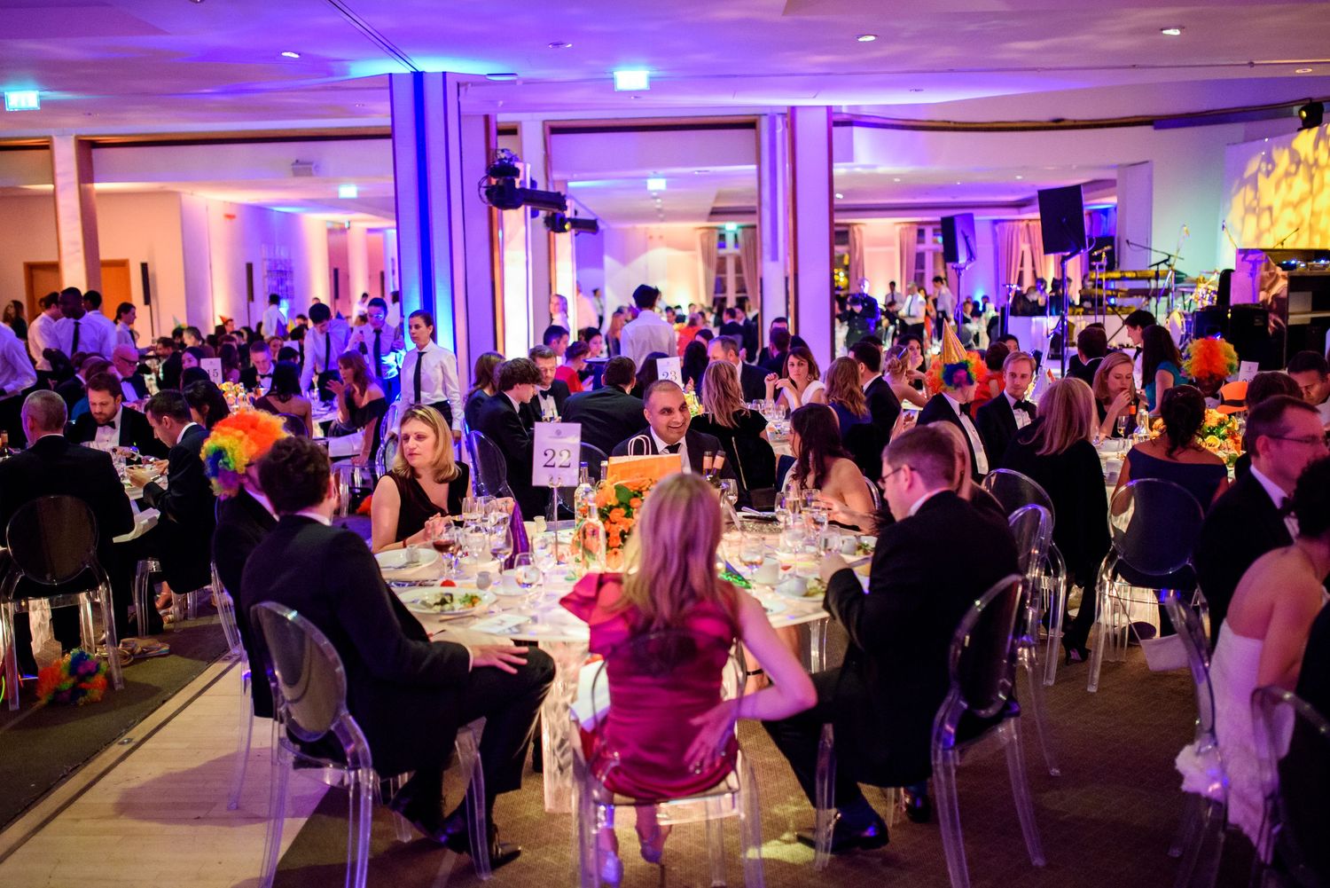 Panoramic view of an elegant wedding reception hall with colorful ambient lighting.