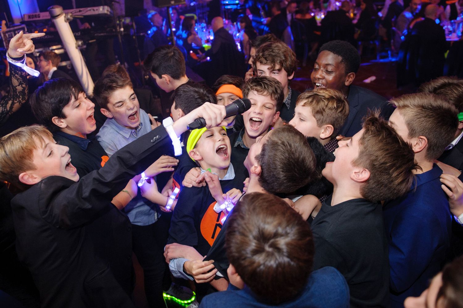 Concert crowd of young people dancing and jumping at a high-energy indoor music performance with blue lighting.