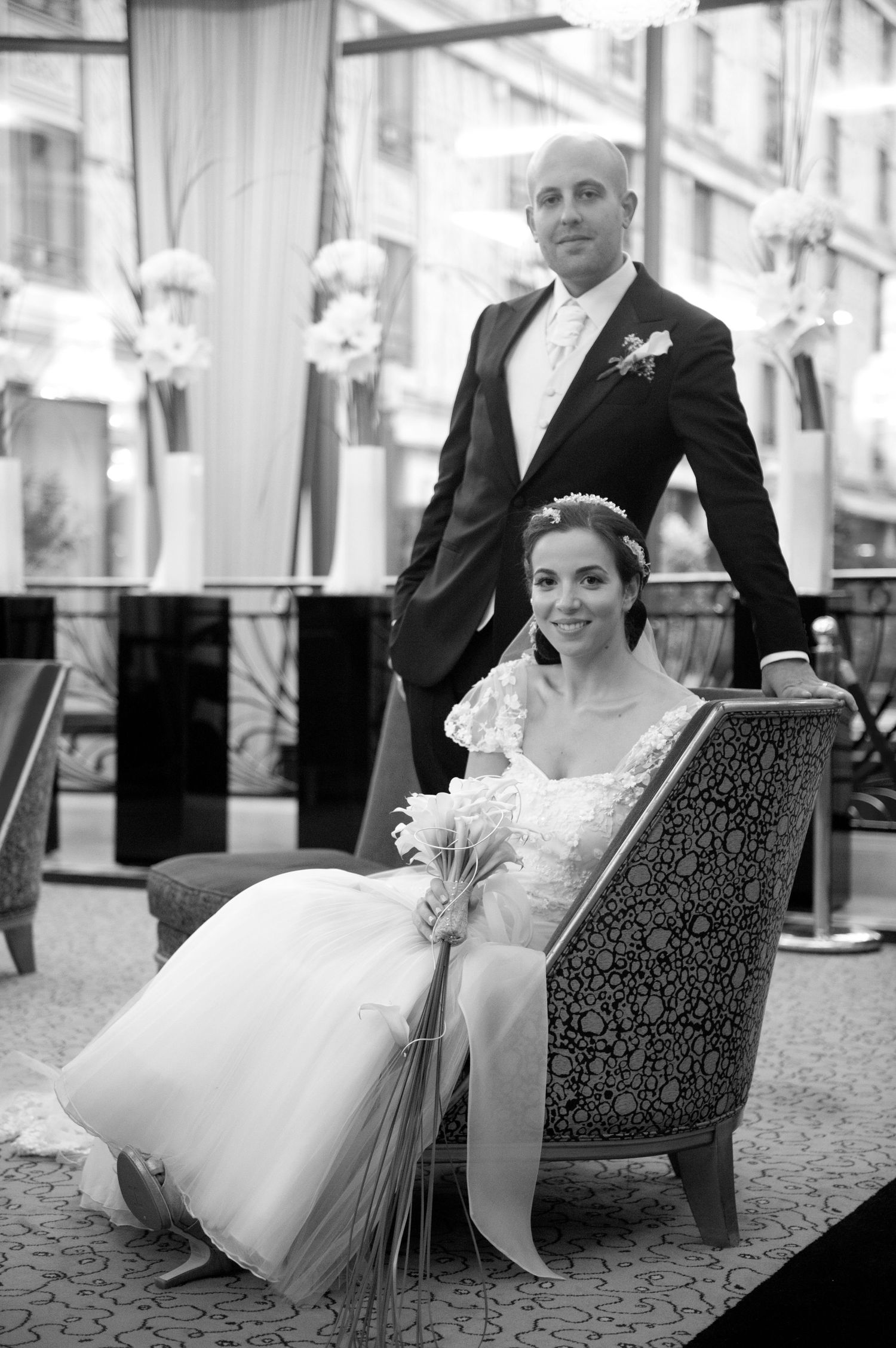 Black and white photo series showing a couple in formal wedding attire seated in elegant chairs at their reception.