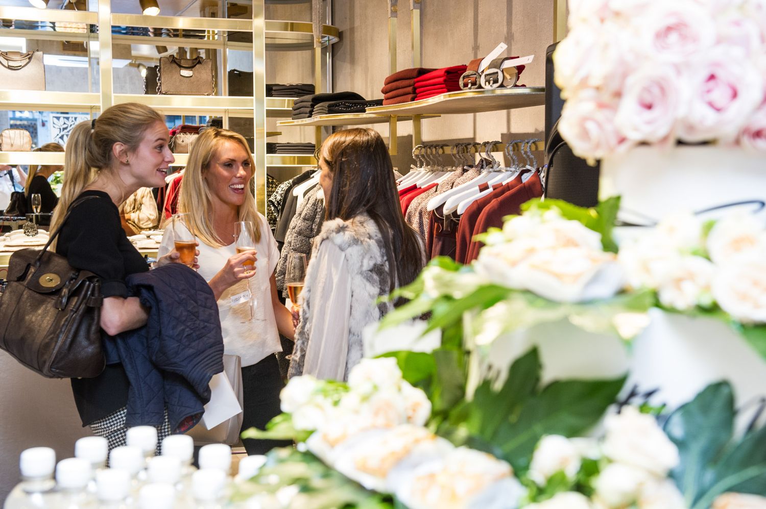 Retail shopping area with clothing displays and floral decorations.