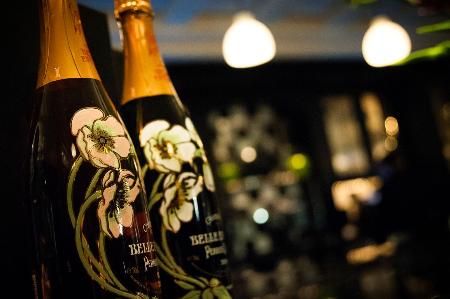 Champagne bottles lined up at an elegant event with soft lighting and glassware.