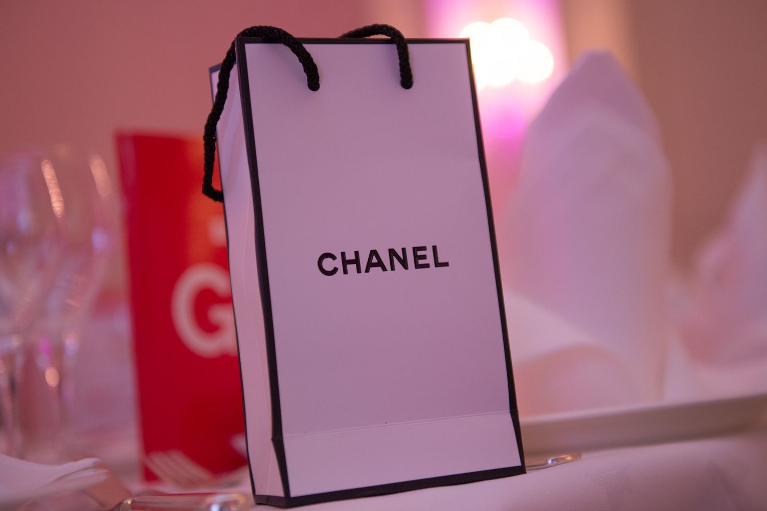 Chanel shopping bags and pink lighting create an upscale retail atmosphere.