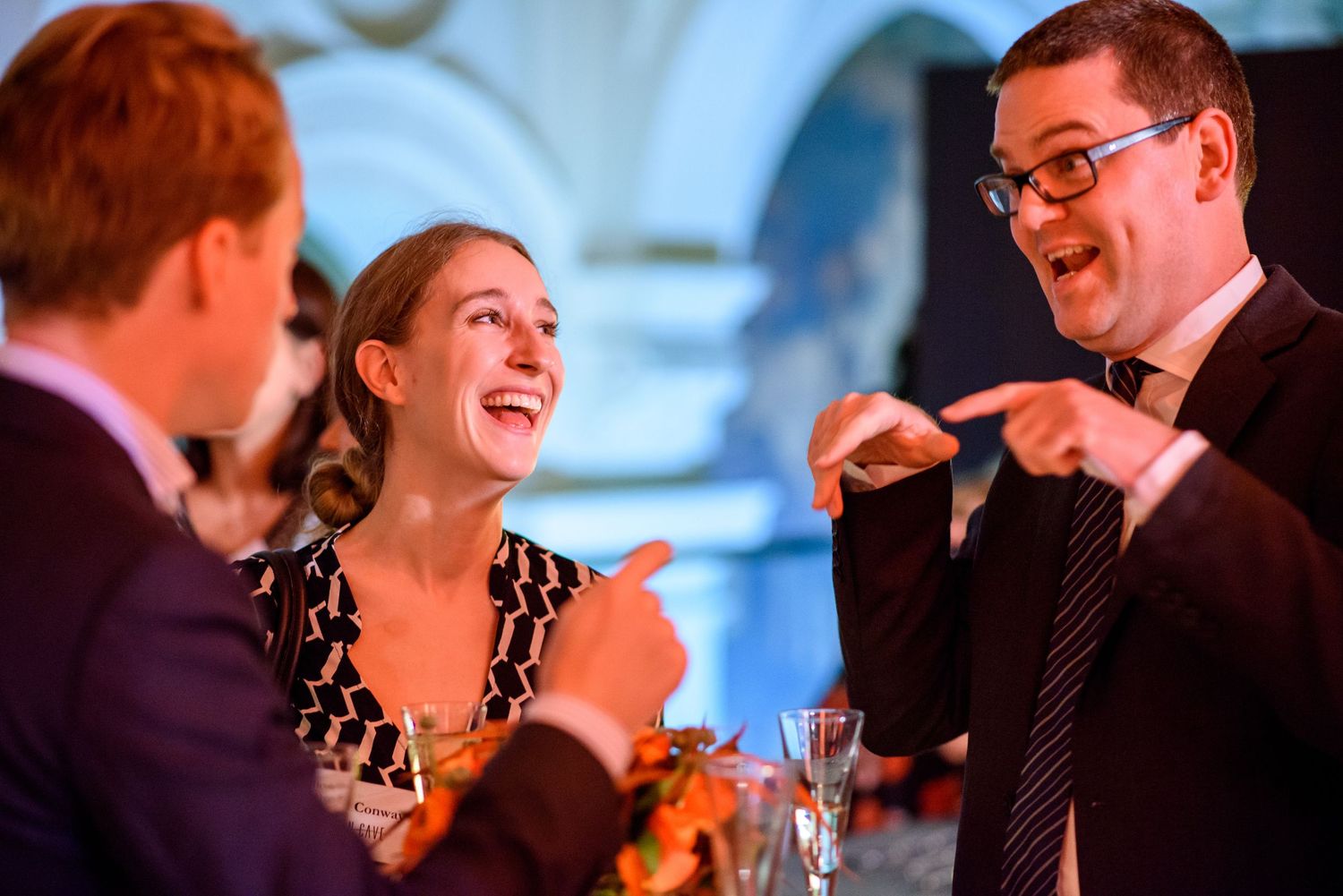 Wedding guests laugh and enjoy themselves during an evening reception celebration.