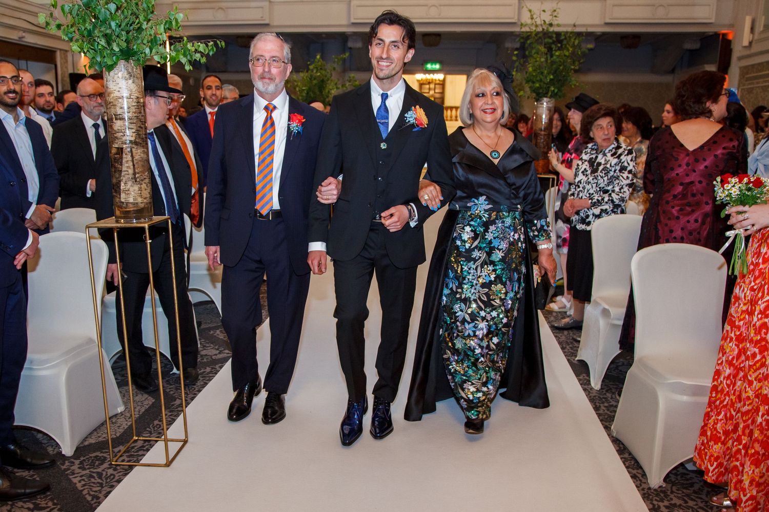 Wedding guests dance and celebrate on a wooden dance floor during an elegant indoor reception.