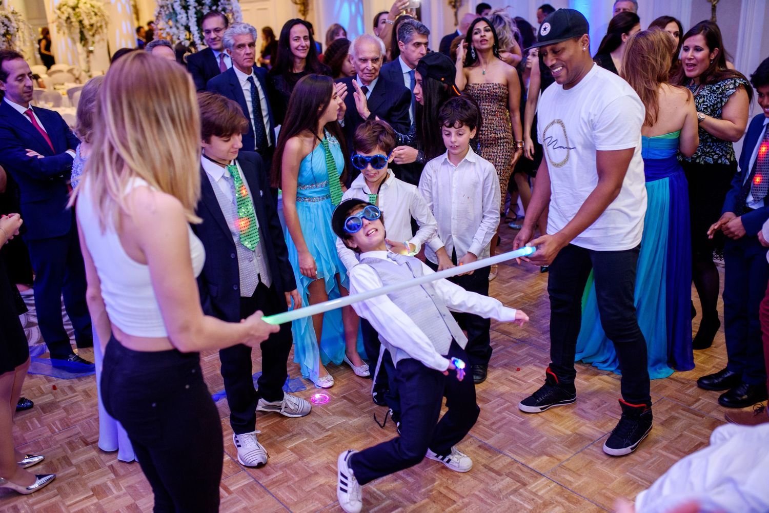 People dancing and celebrating at a wedding reception with colorful lights and decorations.
