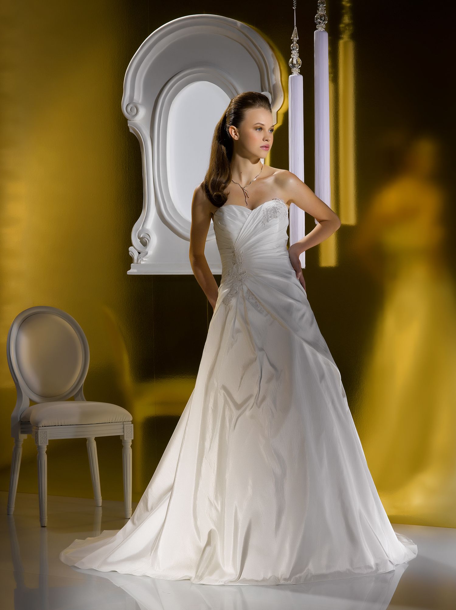 Elegant strapless sweetheart A-line wedding gown with ruched bodice and flowing train displayed in ornate setting.