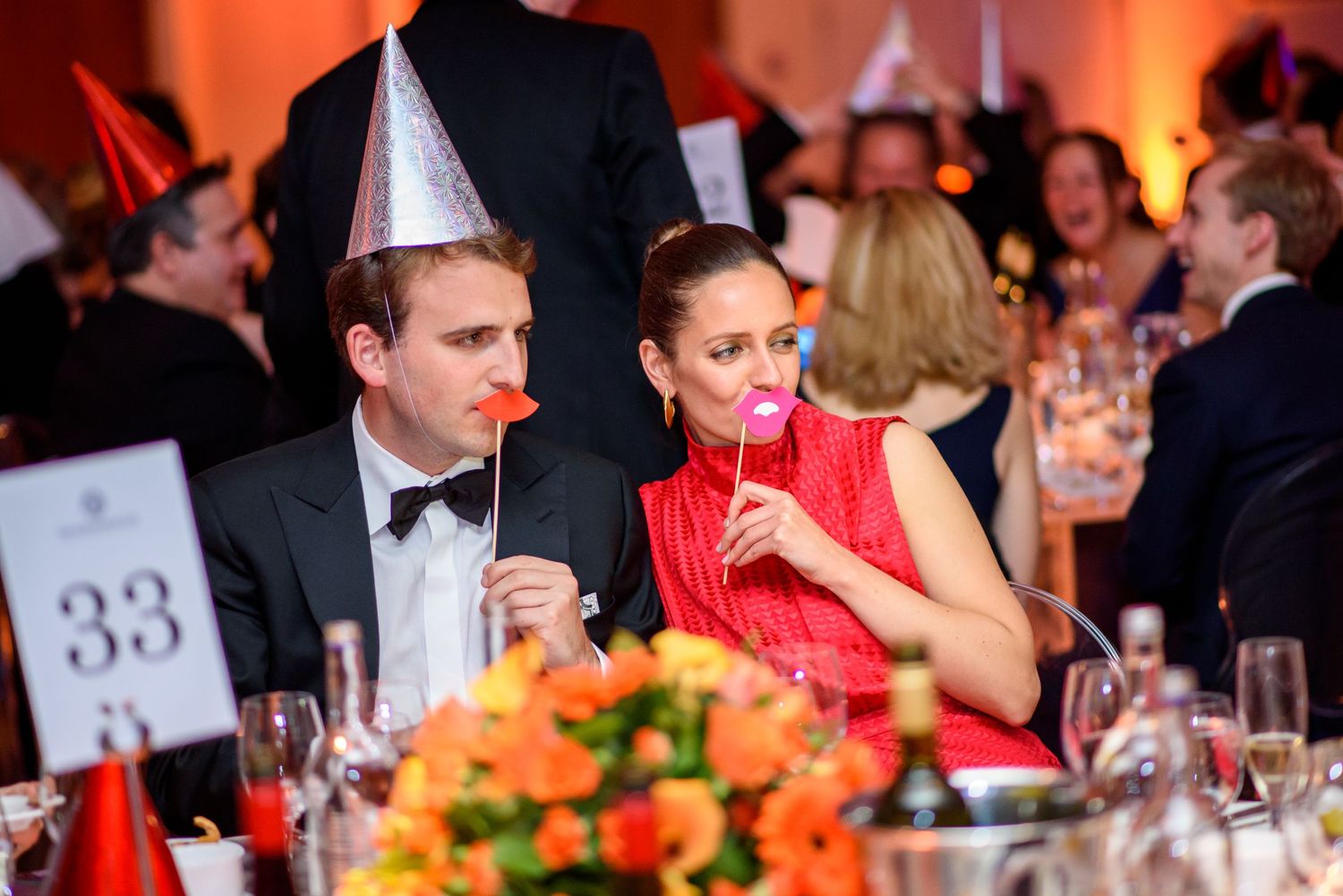 Formal dinner table setting with orange floral centerpieces and elegant place settings.