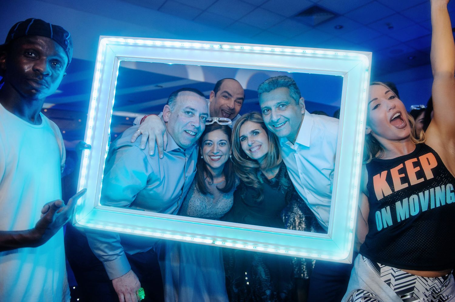 Party scene with blue neon lighting and illuminated frames on the wall.