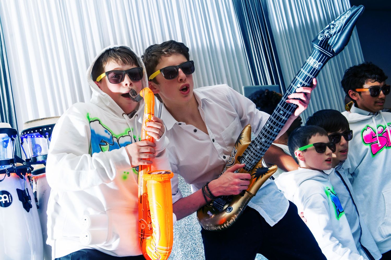 A group of musicians performs with colorful instruments against a blue and white backdrop.