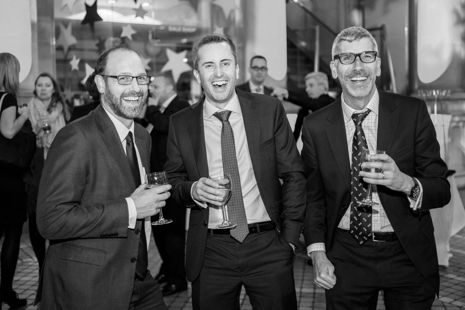 Group of business professionals laughing and socializing at formal event.