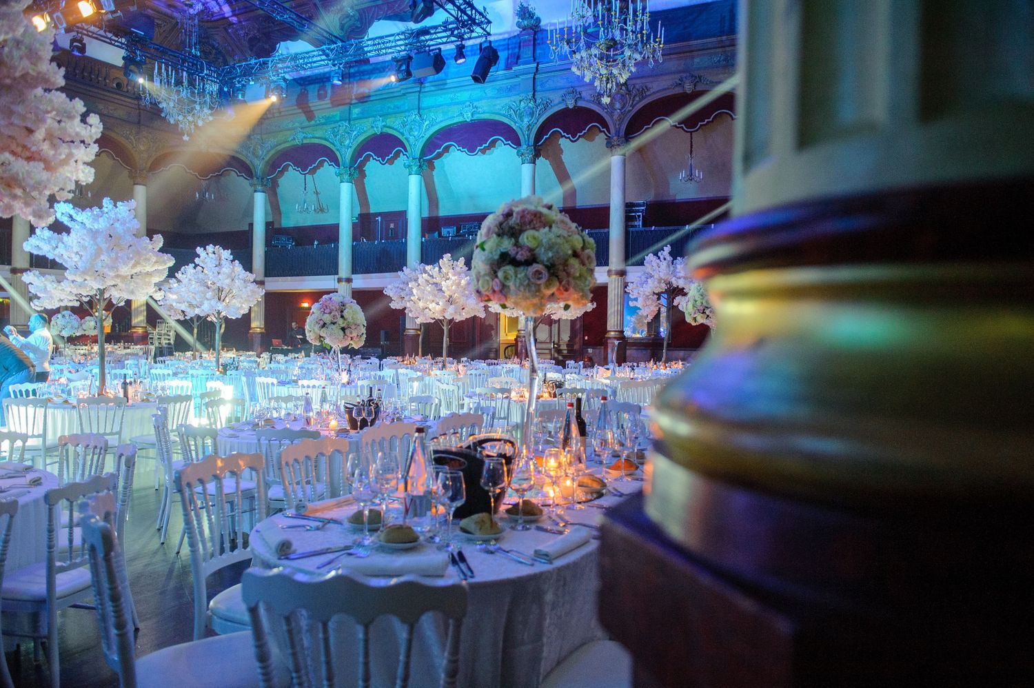Elegant wedding reception venue with crystal chandeliers and blue uplighting creating a romantic atmosphere.